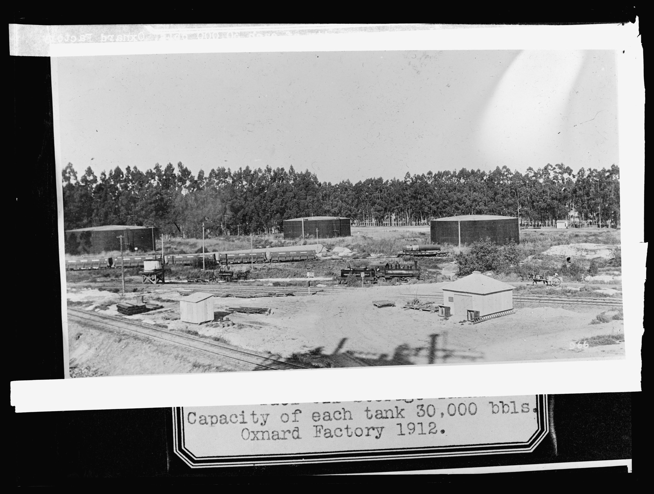 Large cylindrical fuel-oil storage tanks beside railway tracks in Oxnard, California, in an original 1912 archival photograph.